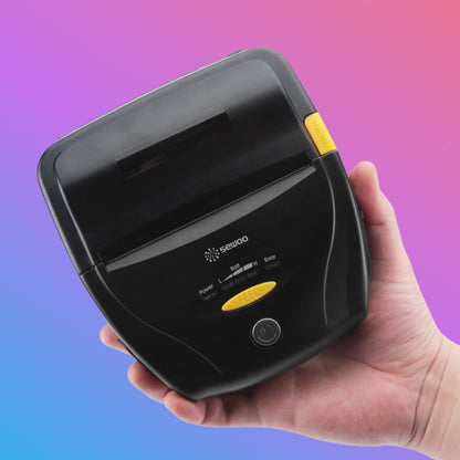 Hand holding a black electronic device with a yellow button against a gradient background