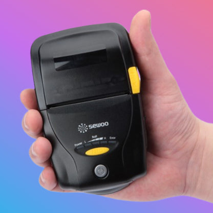 Hand holding a small black device with yellow buttons against a gradient background